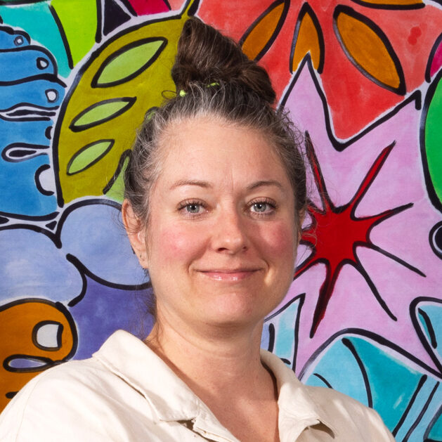Headshot of a Rally Austin board member standing in front of a piece of art depicting flowers.